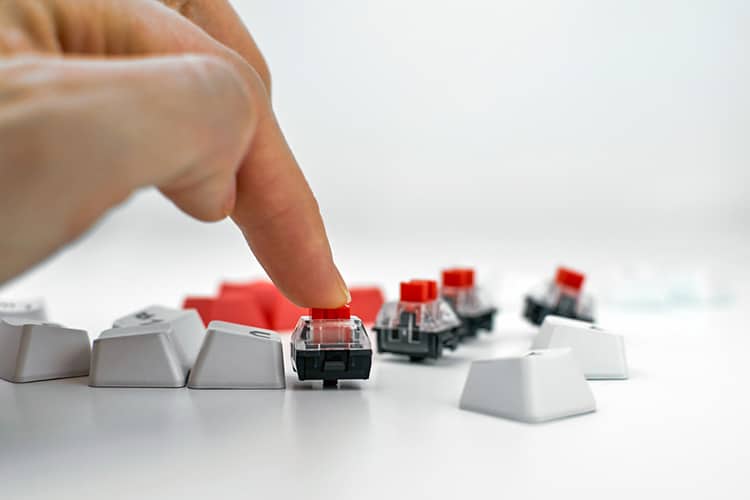 Mechanical keyboard switch on a white background. The person presses the keyboard switch with his finger. Gaming equipment, concept